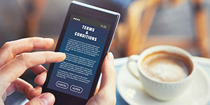 Person clicking a terms and conditions message on their phone in a coffee shop.