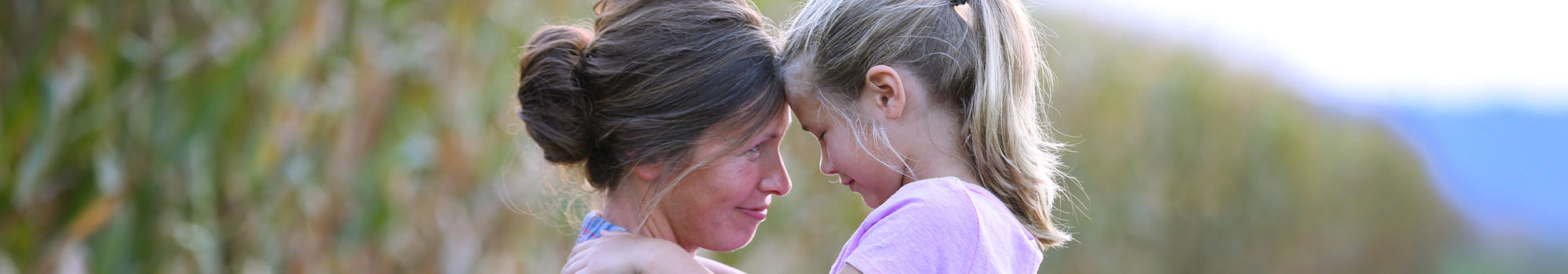 Mom holding daughter in a field of corn