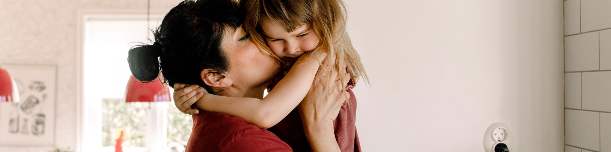 Mom holding her daughter in the kitchen.