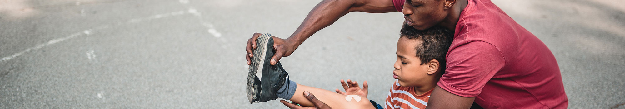 Dad putting a bandage on his son's knee.
