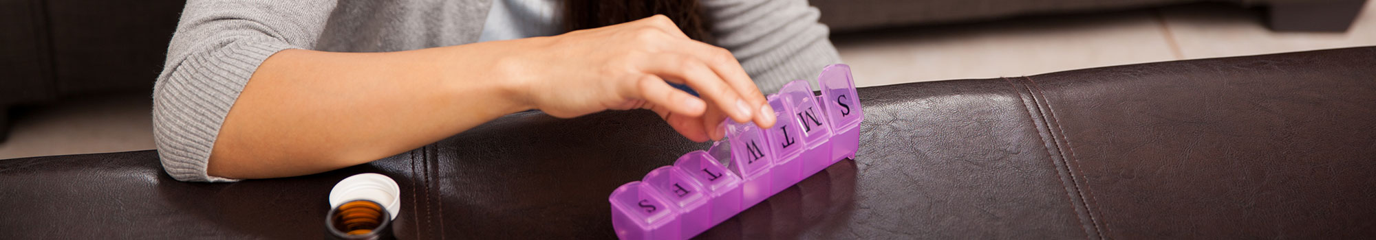 Woman putting medicine in a pill box.