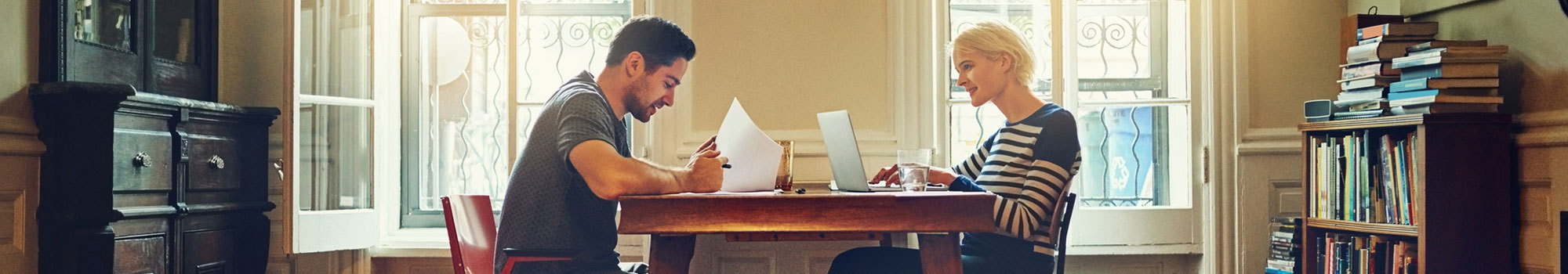Young couple at dinner table analyzing documents to make a decision.
