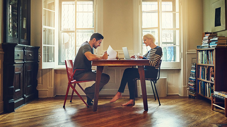 Young couple at dinner table analyzing documents to make a decision.