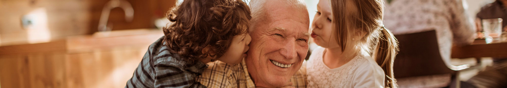 Grandson and granddaughter giving their grandpa a kiss on the cheek.