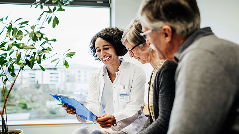 Doctor holding a clipboard and talking with a senior couple