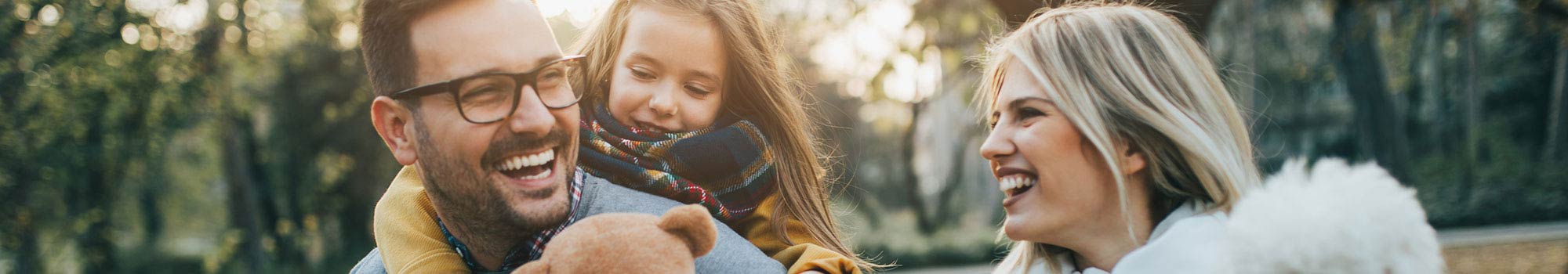 Parents and daughter walking outside in the fall with their dog.