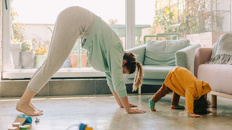 Mom and toddler doing yoga in their living room.