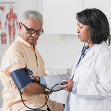 African American doctor checking senior man's blood pressure.
