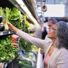 Woman picking fresh product from grocery store aisles.