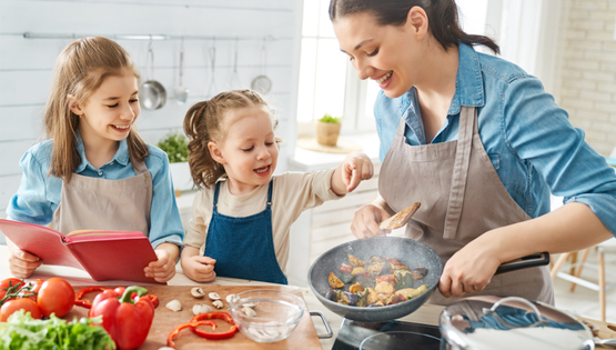 Healthy food at home. Happy family in the kitchen. Mother and children daughters are preparing vegetables.